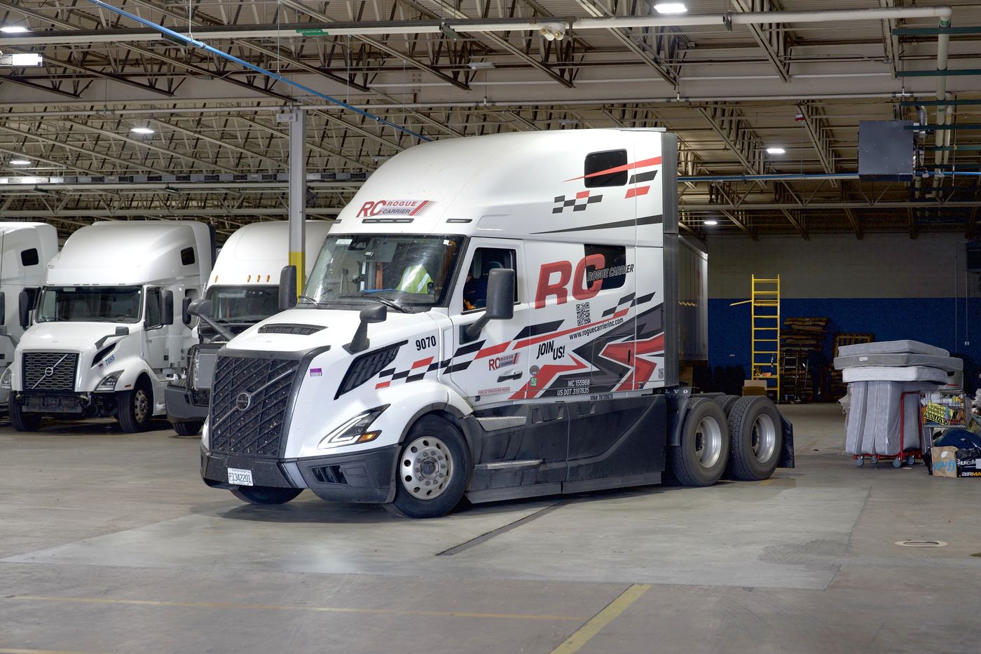 Rogue Carrier wrapped Volvo #9070 in the shop, with more of the fleet behind it